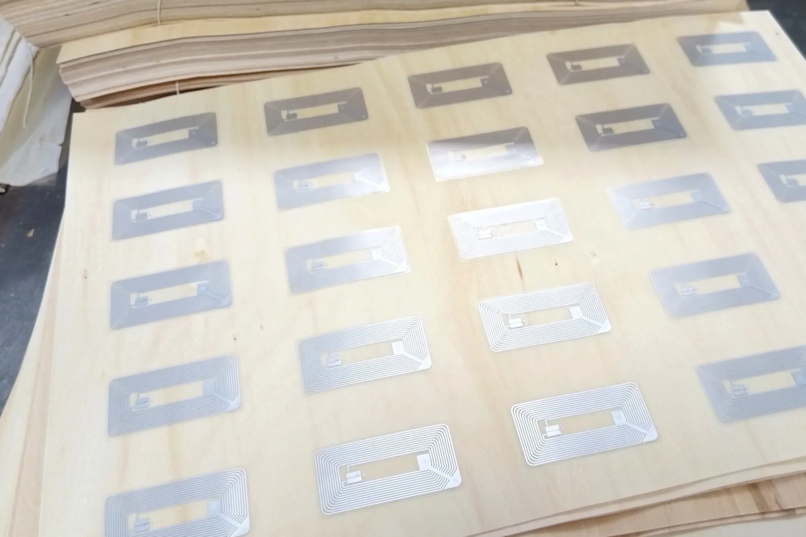 RFID inlays laid out on wood veneer sheets before card pressing