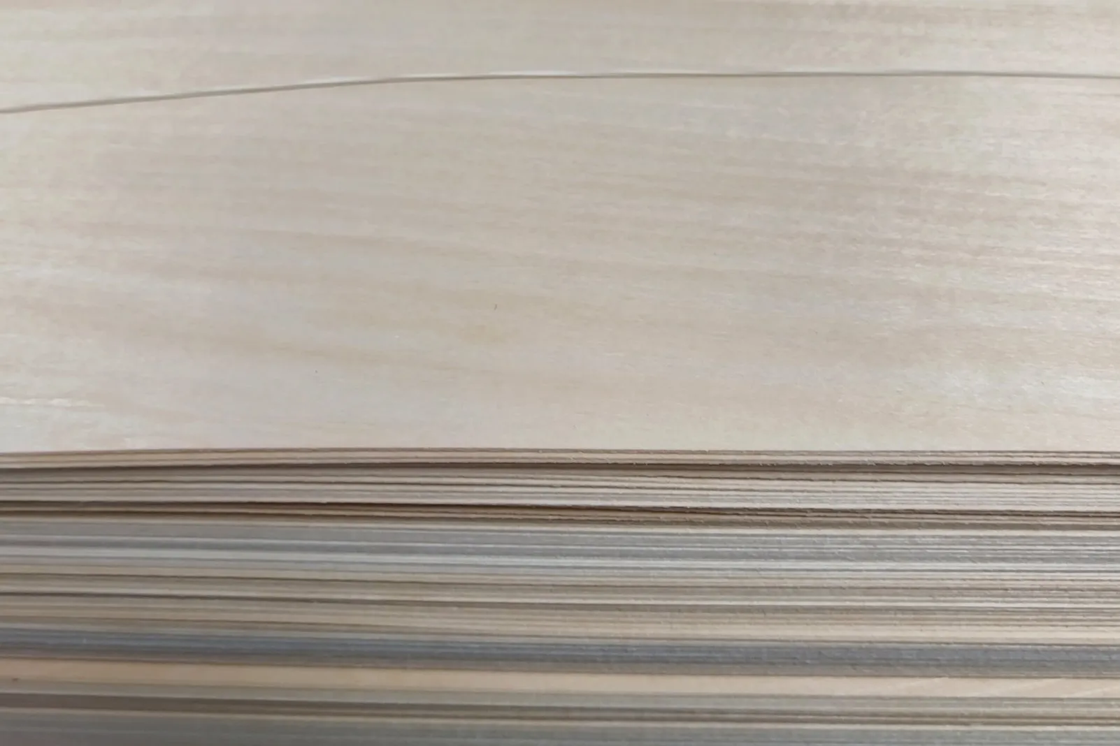 Card-grade veneer sheets stacked in our workshop — graded stock ready for the press.